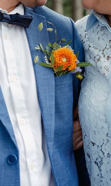 Corsage met oranje dahlia op een blauw kostuum